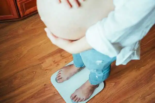 Image of woman weighing herself and experiencing weight gain through pregnancy Sale